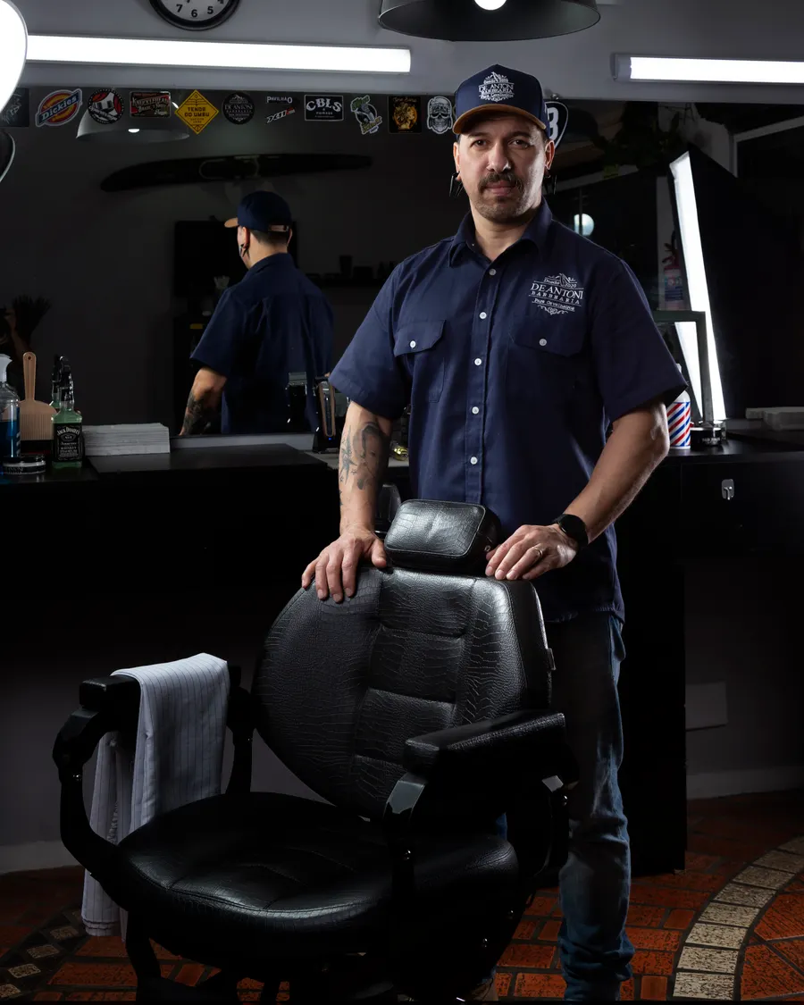 Marcus Alvarez standing behind a black leather barber chair
