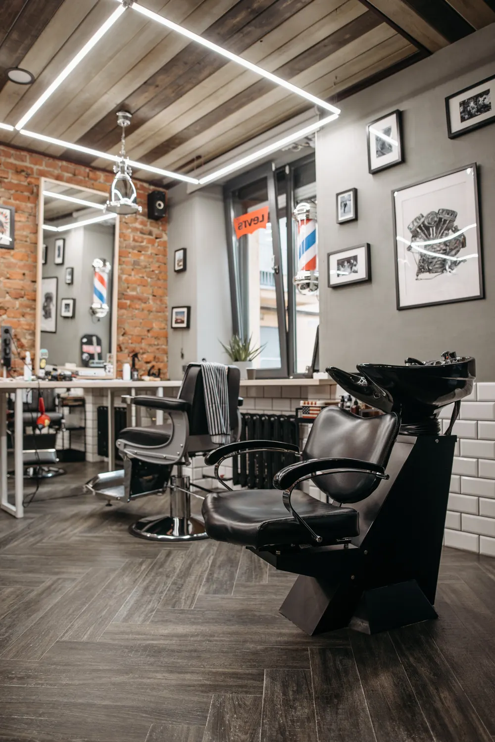 Inside Merzotti: leather barber chairs, brick wall and framed prints